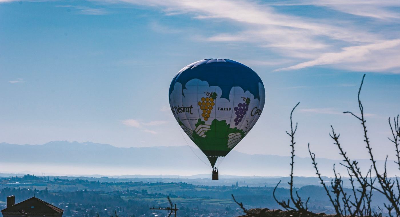 Une montgolfière aux couleurs d’un domaine viticole au-dessus des toits et d’une vallée