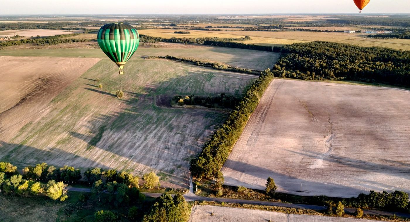 Vue aérienne de deux montgolfières basses au-dessus de champs cultivés