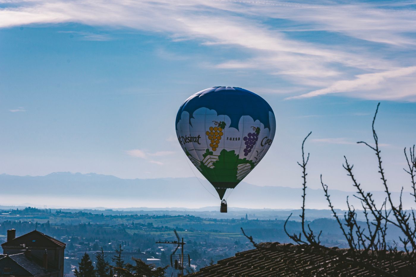Une montgolfière aux couleurs de vignoble survolant la campagne d’Annonay, en Ardèche
